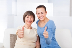 caregiver and senior showing their thumbs up