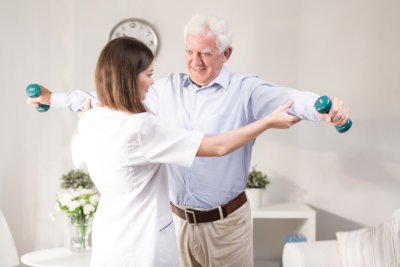 Nurse helping patient to exercise with dumbbels